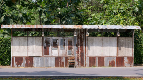 Abandoned built structure on road against plants