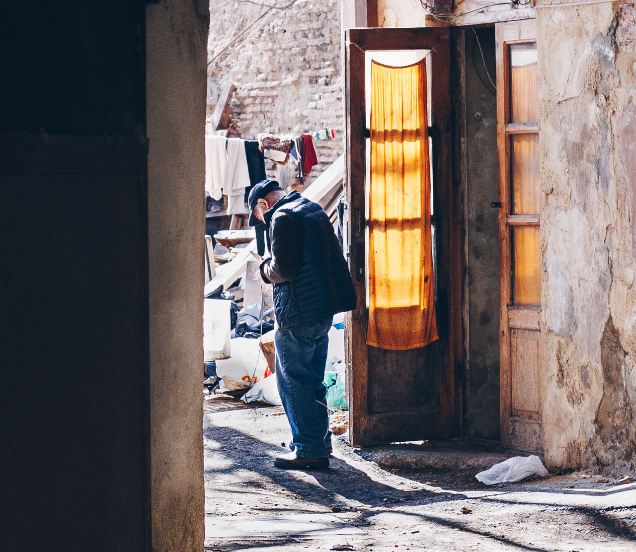 real people, architecture, building exterior, one person, built structure, full length, day, men, lifestyles, standing, building, casual clothing, rear view, entrance, sunlight, door, leisure activity, adult, city, outdoors