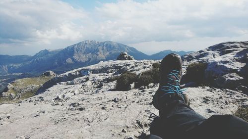 Low section of person relaxing on landscape against sky