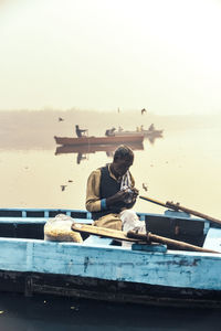 Man sitting on beach against clear sky