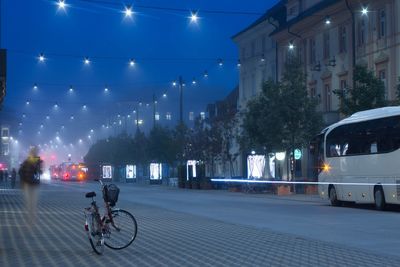 Bicycles parked on illuminated street at night