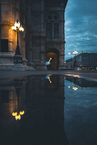 Reflection of illuminated building in water at dusk