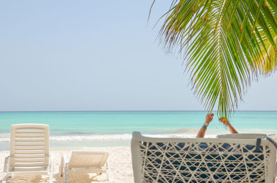 A young man raised his hands in the air while sitting on a chair on the beach, dominicana.