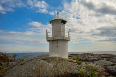 Lighthouse by sea against sky