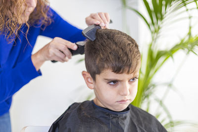 Angry boy getting haircut at home