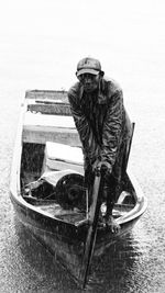 Man standing on boat over sea in rainy season