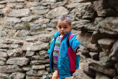 Cute boy standing against stone wall