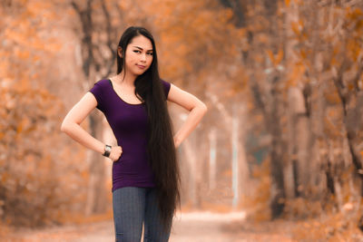 Portrait of a beautiful young woman standing against trees