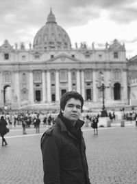 Portrait of young man standing on street against government building