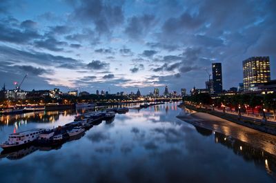 Boats in thames river against cloudy sky at dusk