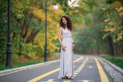 Woman standing on road amidst trees