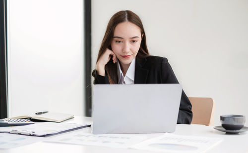 Businesswoman using laptop at desk in office