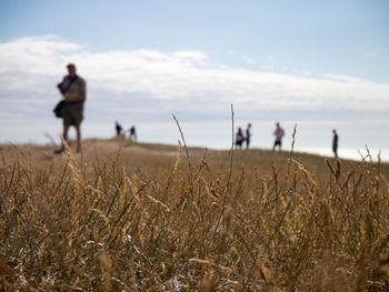 People walking on field against sky