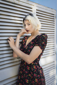 Beautiful young woman standing against wall