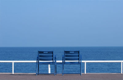 Deck chairs blue on beach against clear blue sky