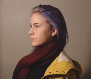 Young woman looking away against brown background