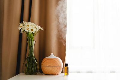 Aromatherapy concept. aroma oil diffuser on the table against the window.