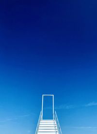 Low angle view of ladder against clear blue sky