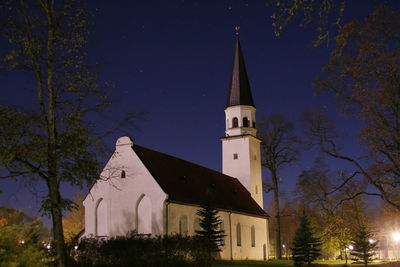 Church by trees against sky at night 