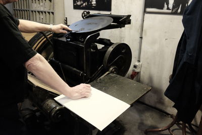 Midsection of typesetter using machinery while working in workshop