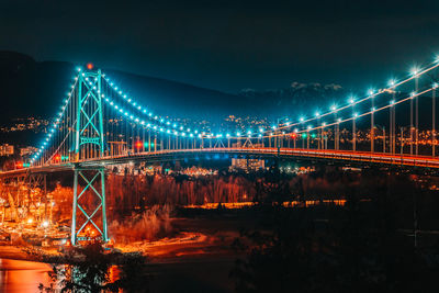 Illuminated bridge over river at night