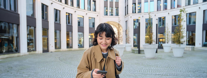 Young woman looking away while standing in city