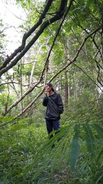 Man standing by tree in forest