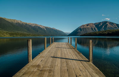 Pier over lake against clear blue sky