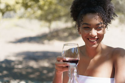 Portrait of smiling young woman drinking glass