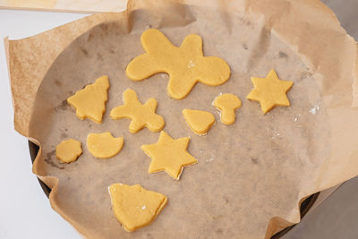 On the parchment are figurines made of raw dough in the form of christmas symbols