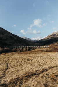 View of arch bridge with mountains in background against blue sky