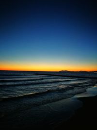 Scenic view of beach against clear sky during sunset