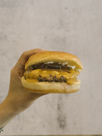 Hand holding single cheese burger with caramalised onions