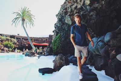 Young man standing on rock against trees