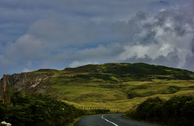 Road amidst green landscape against sky