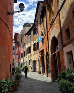 Woman walking in city against sky