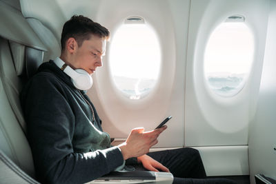 Side view of man using mobile phone while sitting in bus