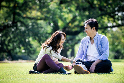 Smiling couple sitting on grass at park