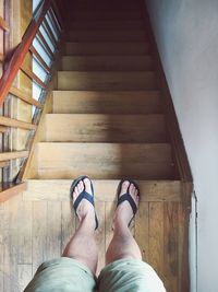 Low section of man standing on wooden steps at home