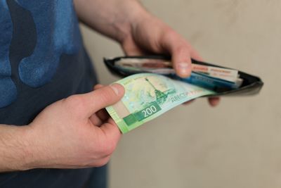 Midsection of man removing paper currency from wallet