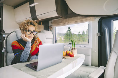 Happy woman using laptop sitting on table in motor home