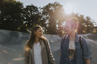 Smiling teenage girls talking together at skate park