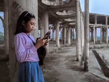 Side view of woman using mobile phone in building