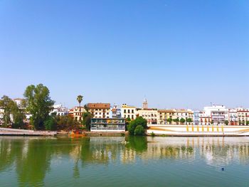 River in city against clear blue sky