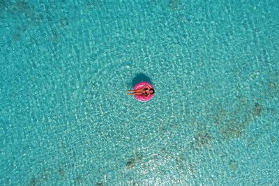 Aerial view of teenage girl sitting on inflatable ring in sea