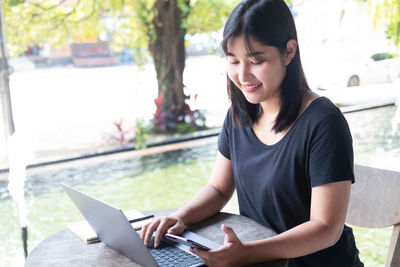 Smiling young woman using smart phone