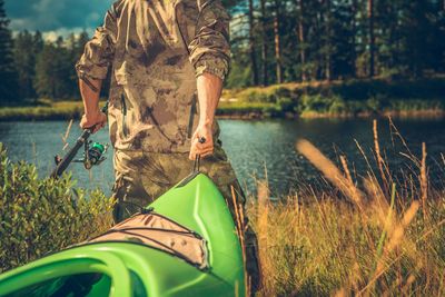 Midsection of man pulling kayak while walking on field