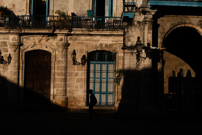 Woman standing by window of old building