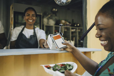 Happy female customer doing contactless payment at food truck