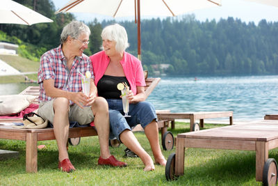 Senior couple sitting against lake at resort